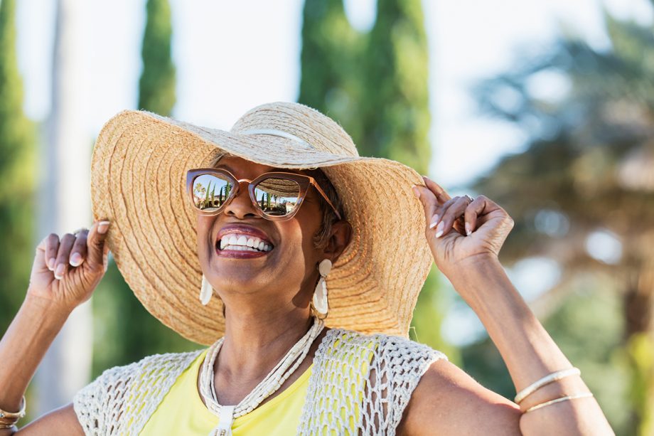 a woman in a straw hat and sunglasses smiles