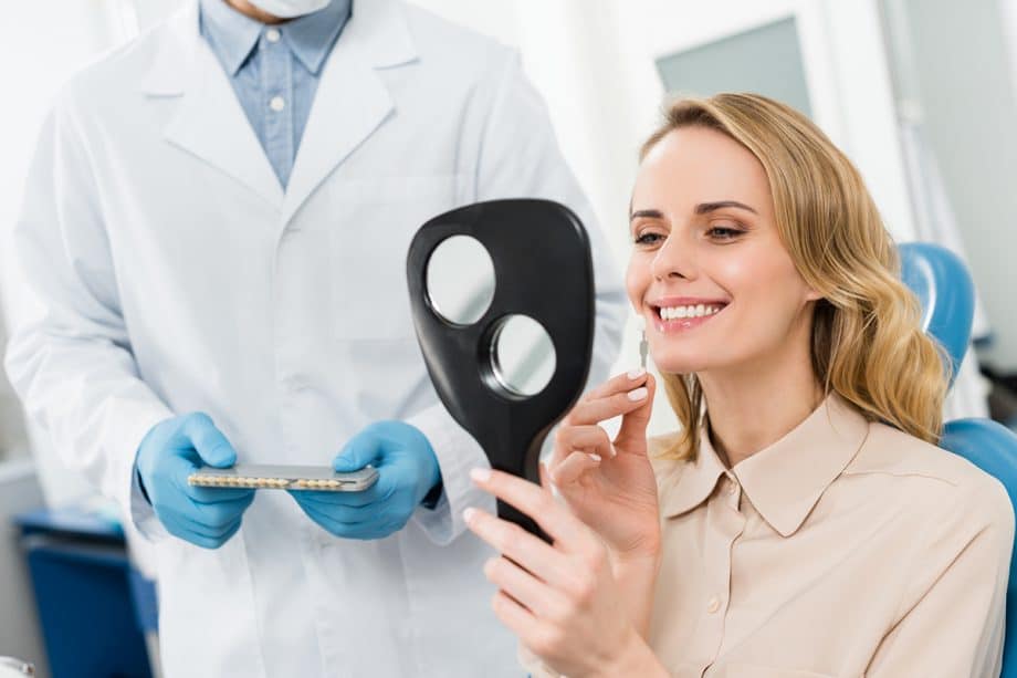 a dentist shows a patient her new veneers in a mirror