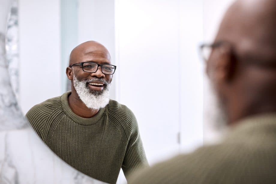 a man smiles into a mirror after a teeth whitening