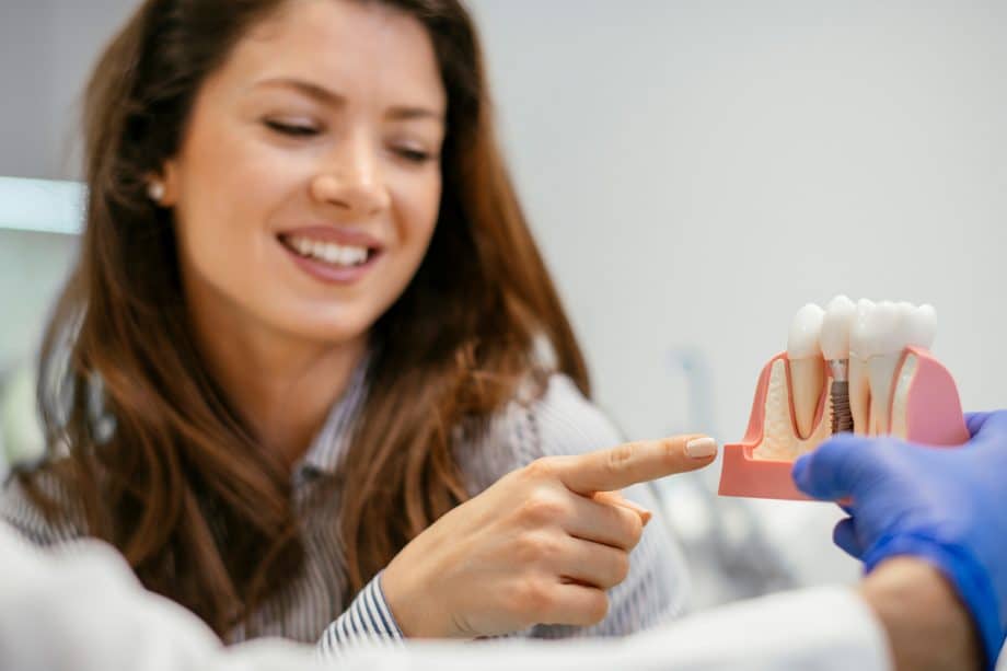 a dentist explains a dental implant model